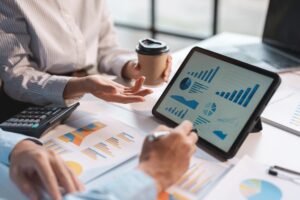 bookkeeping reports displayed on a laptop screen and being discussed by two people over coffee in a board room