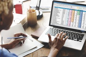 bookkeeping reports displayed on a laptop screen and being discussed by two people over coffee in a board room