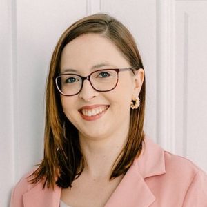 Headshot of Jo Mahaney, communications manager, in pink blazer against a white background