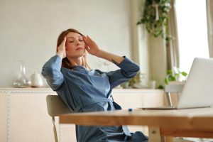 Stressed out CEO woman rubs her hands to her temple as if she has a headache.