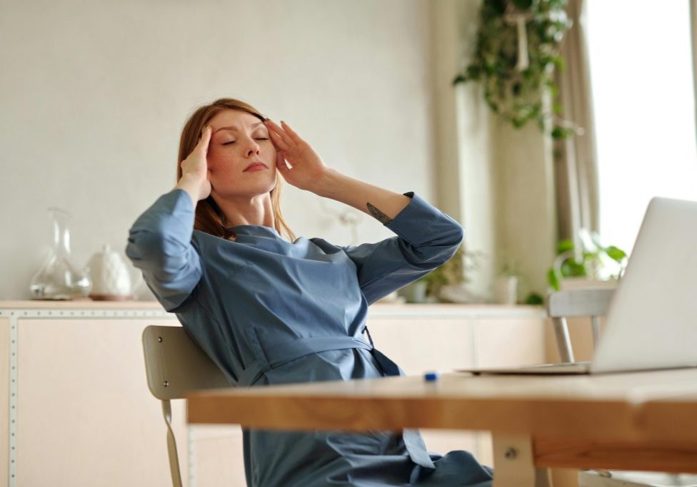 Stressed out CEO woman rubs her hands to her temple as if she has a headache.